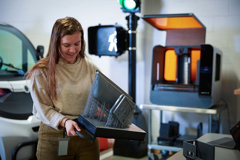 Woman holding build platform with 3D print made from resin.